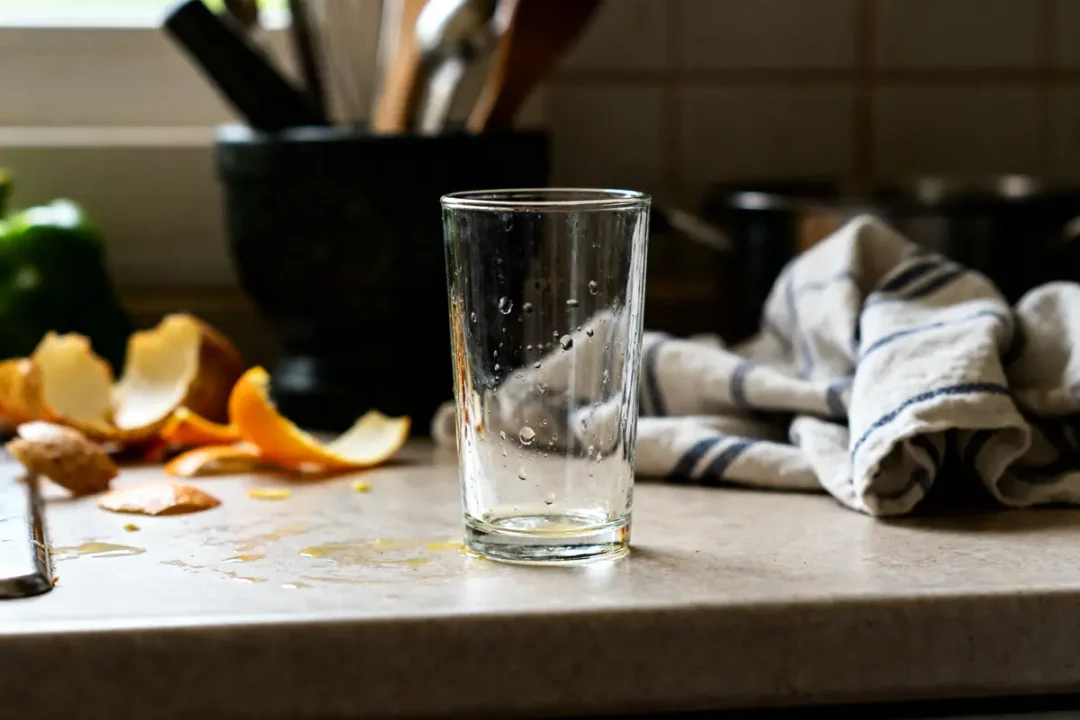 Verre vide sur comptoir de cuisine avec 1/8 de litre en ml d'eau éclaboussée.