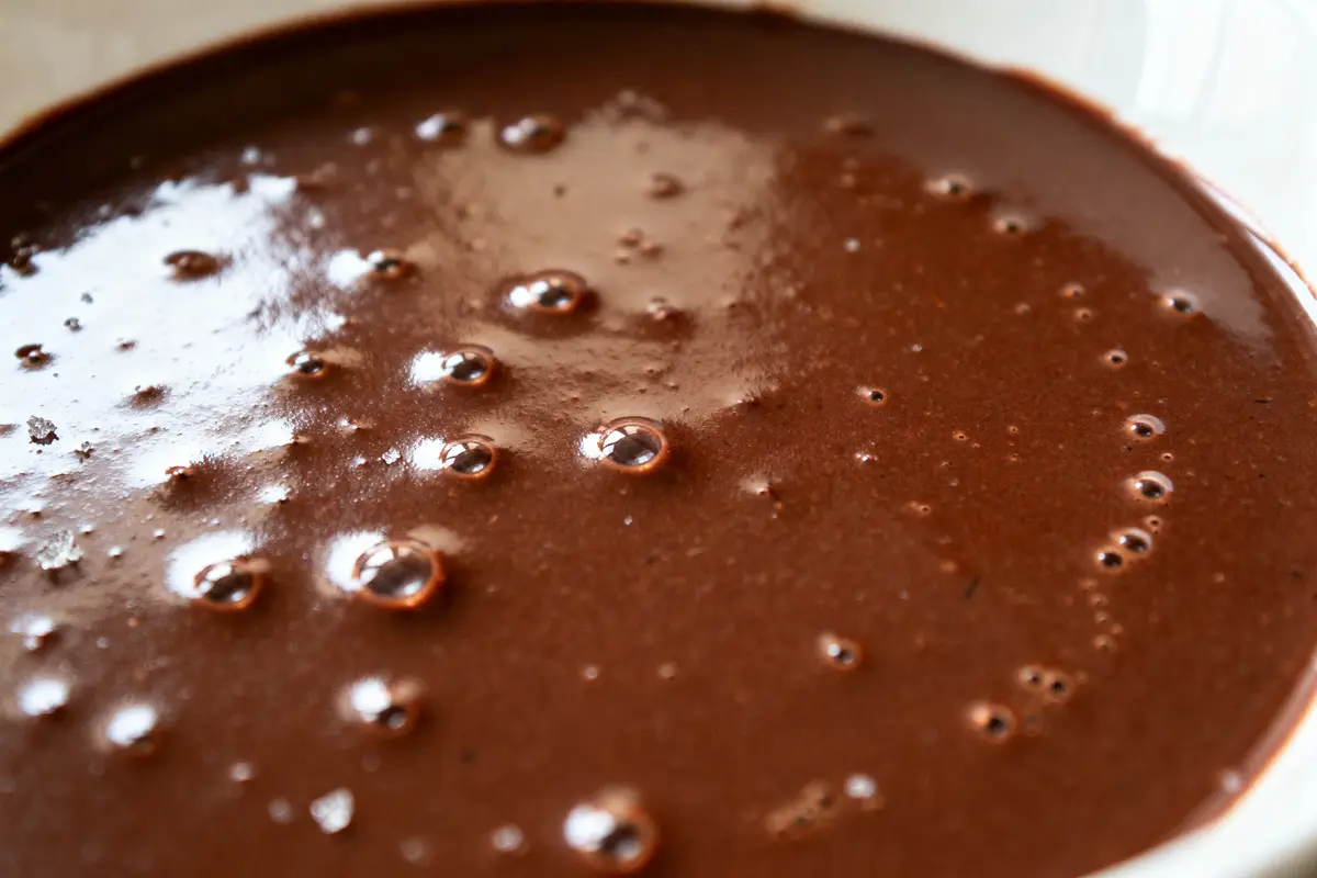 Texture onctueuse de sauce chocolat pour profiteroles avec bulles appétissantes en surface