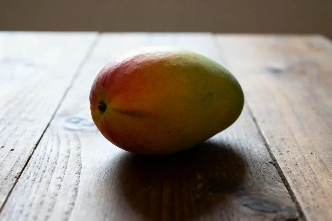 Mangue mûre sur table en bois illustrant comment savoir si une mangue est mûre
