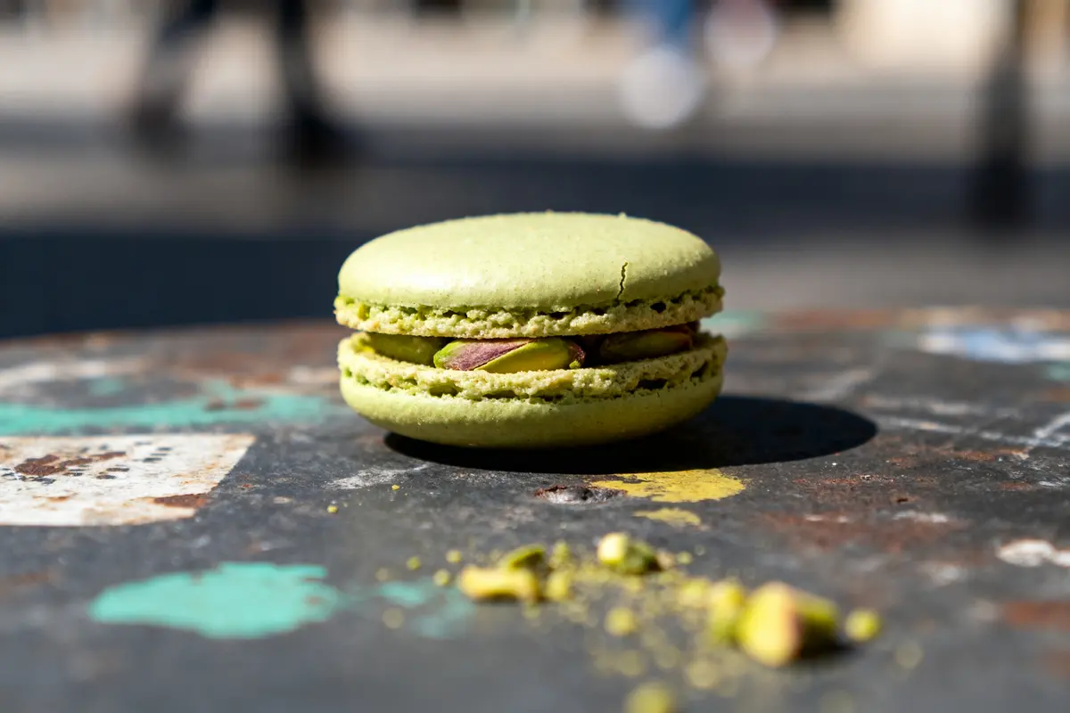 Macaron à la pistache sur table en métal avec éclats de pistache autour