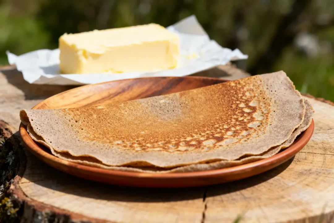 Galette de sarrasin sur une assiette en bois avec beurre pour recette de galette rustique