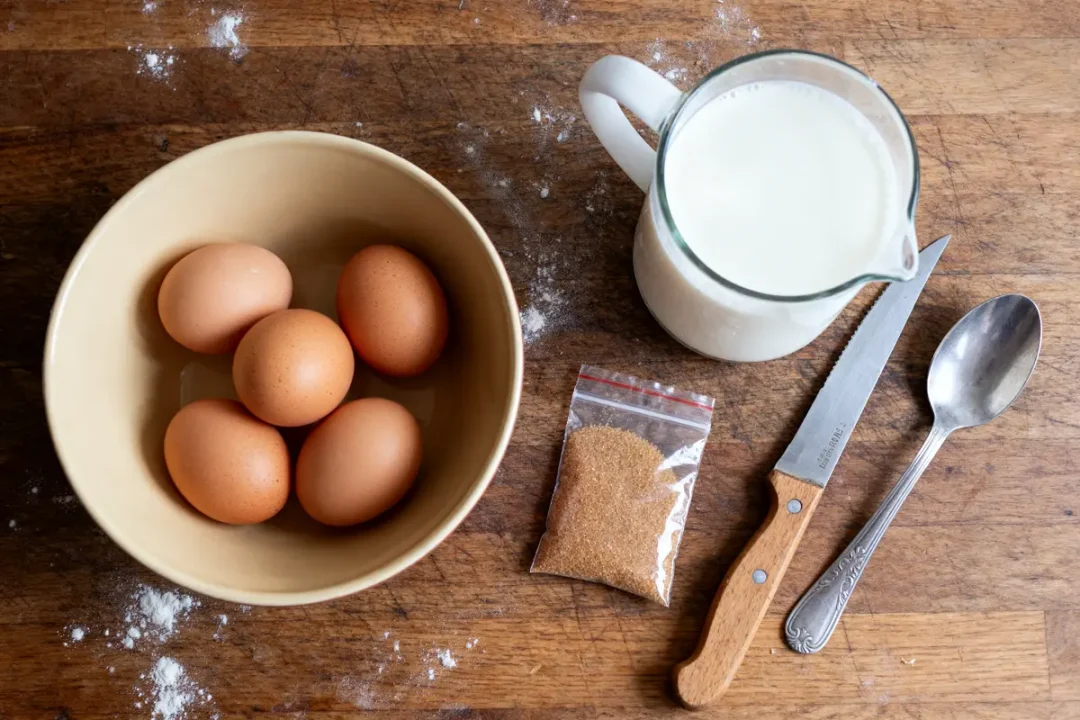 Ingrédients de la recette des oeufs au lait grand-mère avec lait et oeufs sur table en bois