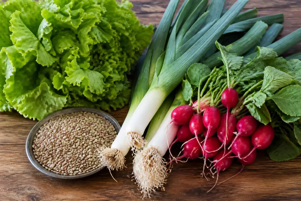 Légumes frais comprenant laitue, poireaux et radis avec assiette de graines de lin